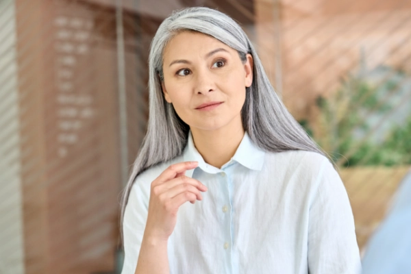 Older Asian woman with grey hair questioning the real estate market.